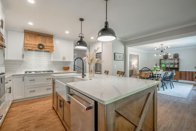 kitchen featuring white cabinetry, stainless steel appliances, an island with sink, and pendant lighting