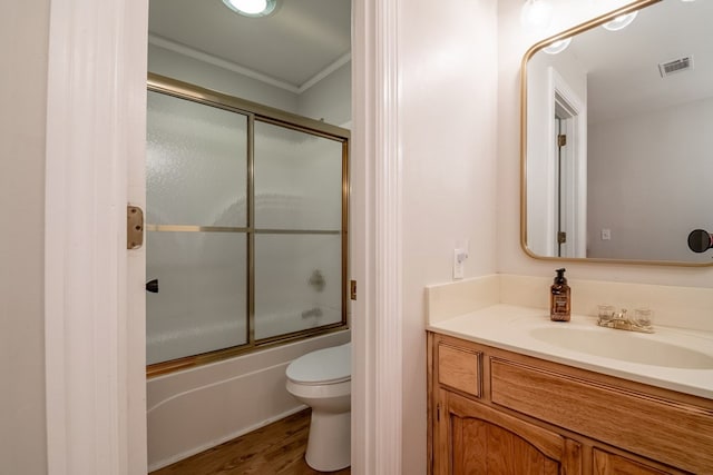 full bathroom with toilet, vanity, ornamental molding, hardwood / wood-style flooring, and enclosed tub / shower combo