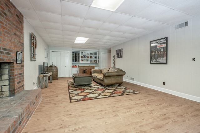 living room featuring a drop ceiling and light wood-type flooring