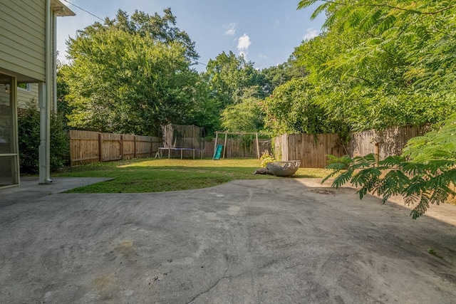 view of yard featuring a trampoline, a patio area, and a playground