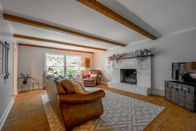 living room with a brick fireplace, beam ceiling, and light hardwood / wood-style flooring