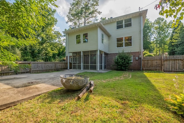 back of property with a sunroom, a fire pit, and a lawn