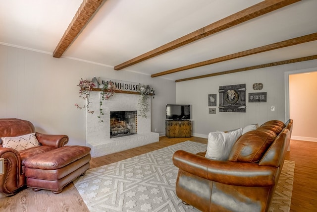 living room featuring a brick fireplace, light hardwood / wood-style flooring, and beamed ceiling