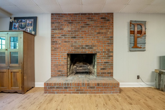 living room with light hardwood / wood-style flooring, a fireplace, and a paneled ceiling