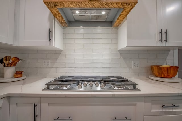 kitchen with white cabinets, light stone counters, and wall chimney exhaust hood