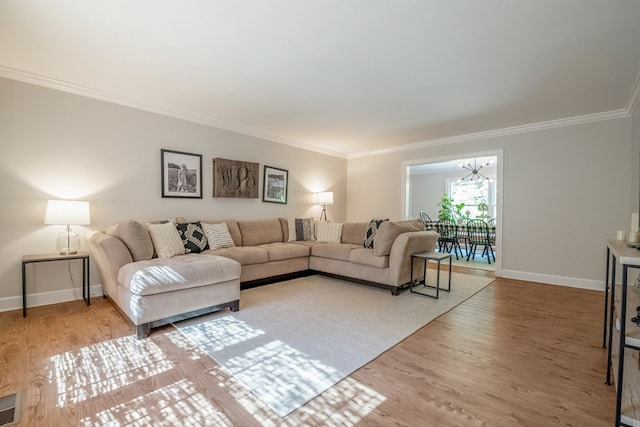 living room featuring hardwood / wood-style flooring, crown molding, and an inviting chandelier