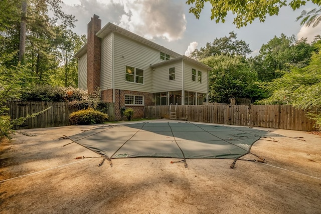 rear view of property with a covered pool and a patio area