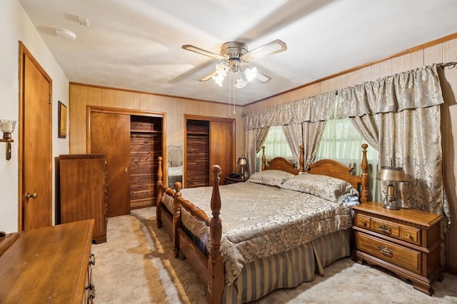 183 Long Hollow Rd, Rock Spring, GA 39736 - bedroom featuring wooden walls, light colored carpet, crown molding, two closets, and a ceiling fan