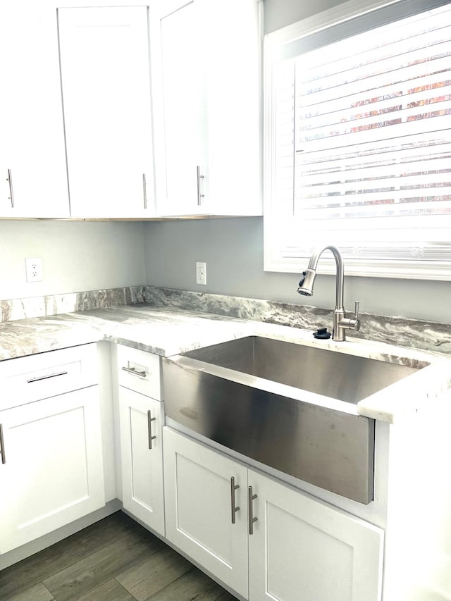 kitchen featuring light stone counters, dark hardwood / wood-style flooring, sink, and white cabinets