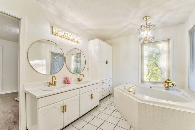 432 Castle Rd, Dalton, GA 30720 - bathroom with an inviting chandelier, vanity, tiled bath, a textured ceiling, and tile patterned floors