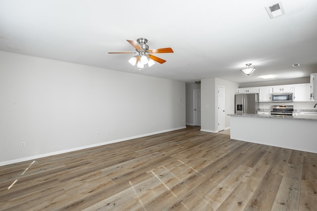 unfurnished living room with ceiling fan, sink, and light wood-type flooring