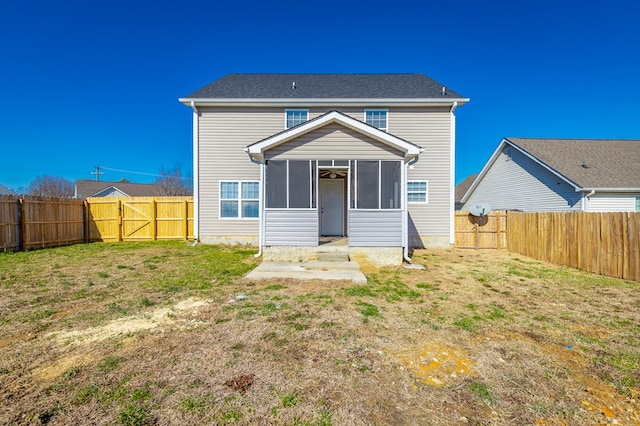 rear view of house featuring a yard and a sunroom