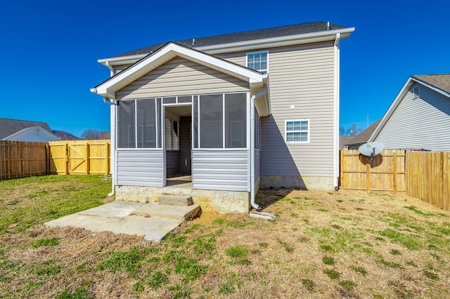 rear view of house featuring a lawn and a sunroom