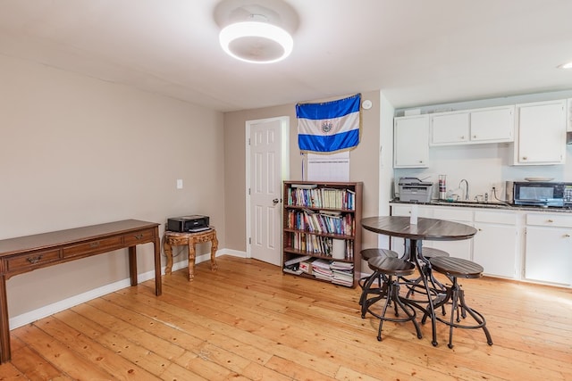 kitchen with sink, white cabinets, and light wood-type flooring