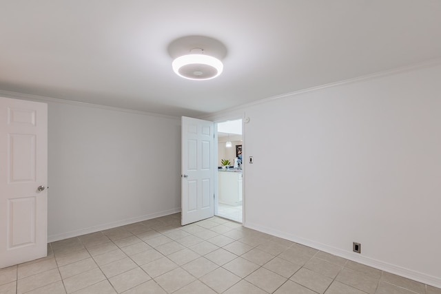 empty room featuring crown molding and light tile patterned floors