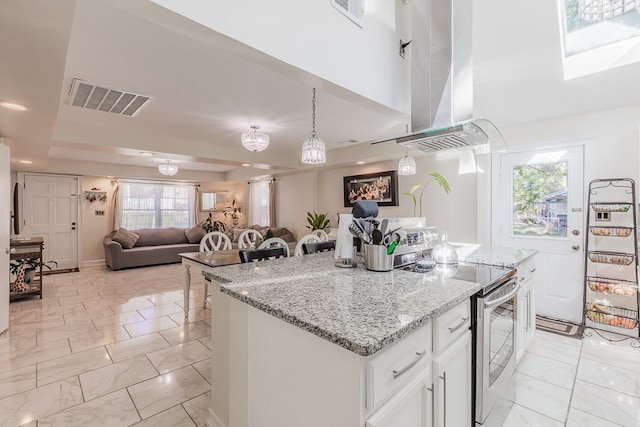 kitchen featuring pendant lighting, white cabinets, a kitchen breakfast bar, a center island, and electric stove