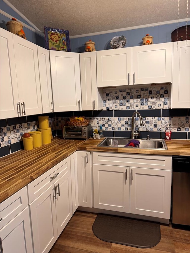 kitchen with a sink, wood counters, white cabinetry, decorative backsplash, and stainless steel dishwasher