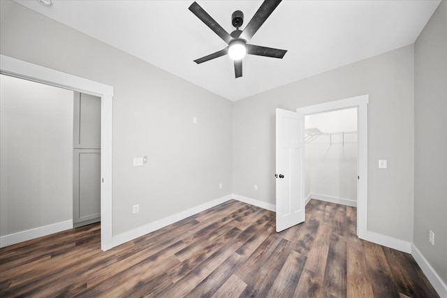 unfurnished bedroom featuring ceiling fan, a walk in closet, dark hardwood / wood-style flooring, and a closet