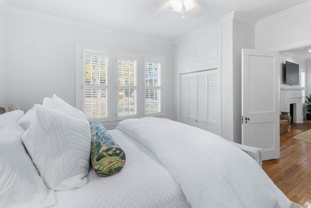 bedroom with crown molding, ceiling fan, hardwood / wood-style floors, and a closet