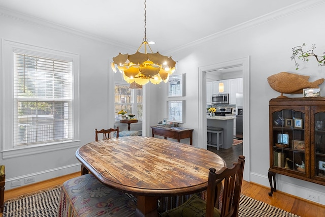 dining room with light hardwood / wood-style flooring, ornamental molding, and a chandelier