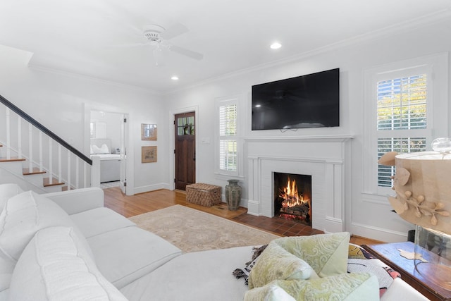 living room with hardwood / wood-style flooring, ceiling fan, and ornamental molding