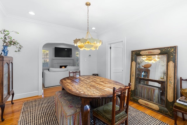 dining room with a notable chandelier, crown molding, and light hardwood / wood-style flooring