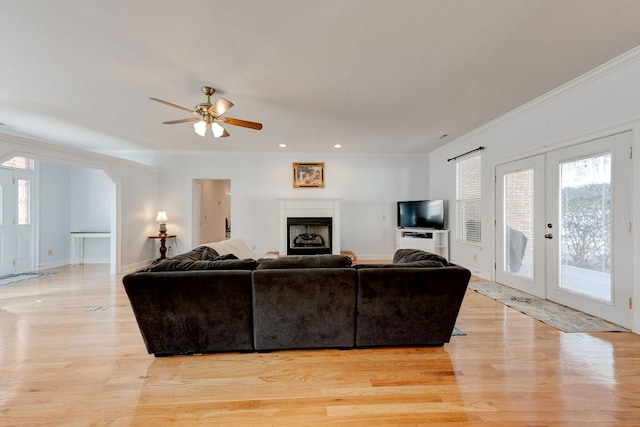 living room with crown molding, french doors, ceiling fan, and light wood-type flooring