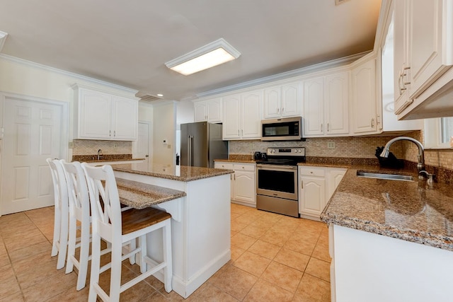 kitchen with stainless steel appliances, sink, a kitchen island, and white cabinets