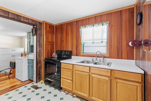 kitchen featuring black / electric stove, washer and clothes dryer, sink, and wood walls