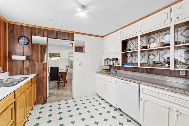 kitchen with white cabinetry, white dishwasher, sink, and wood walls