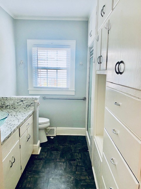 bathroom with vanity, an enclosed shower, ornamental molding, and toilet