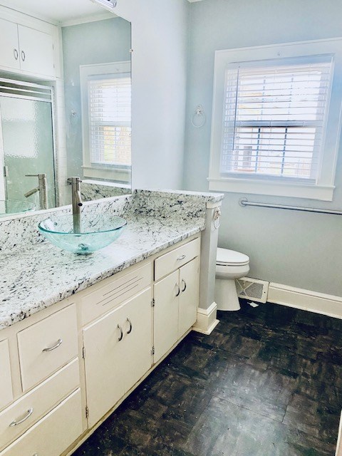 bathroom featuring vanity, toilet, and a shower with shower door