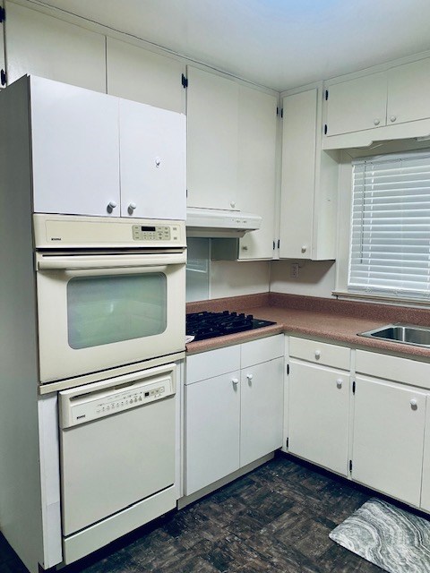 kitchen with white cabinetry, sink, and white appliances