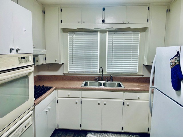 kitchen featuring white appliances, sink, and white cabinets