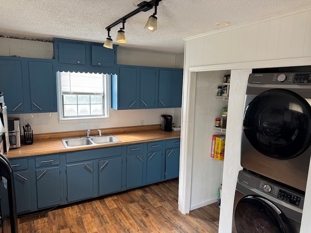 kitchen with blue cabinets, stacked washer and clothes dryer, and a sink