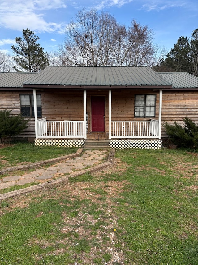 view of front of house with covered porch, metal roof, and a front yard