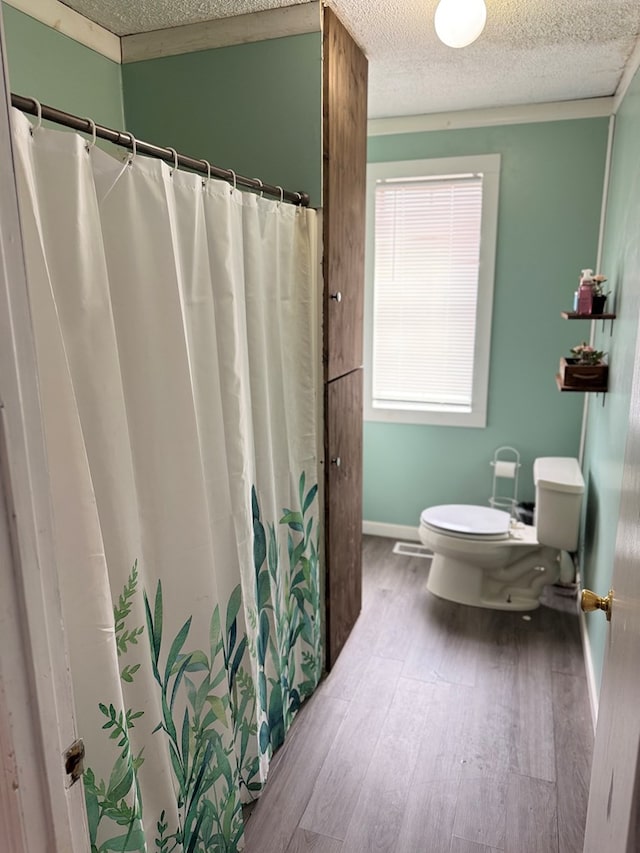 bathroom featuring visible vents, toilet, a textured ceiling, wood finished floors, and baseboards