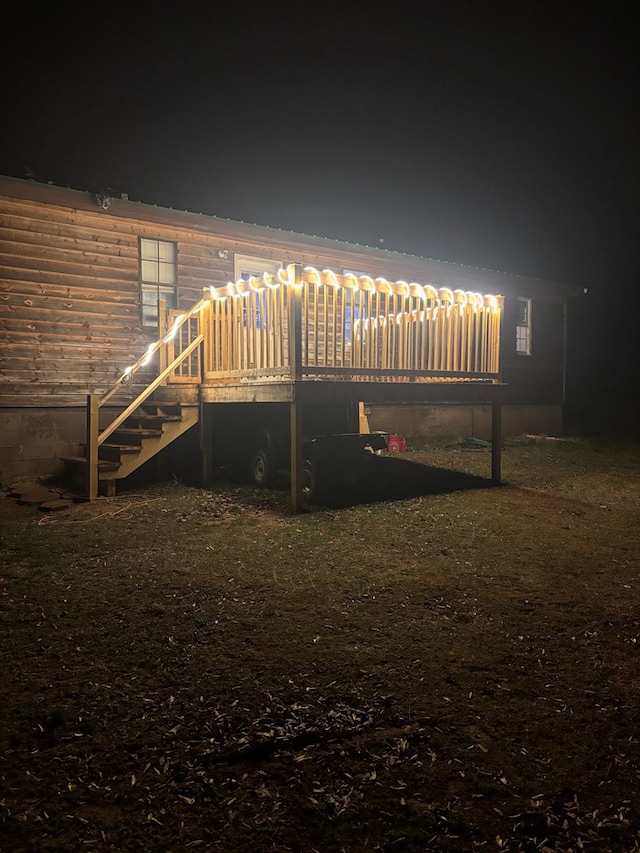 back of house at night featuring a wooden deck