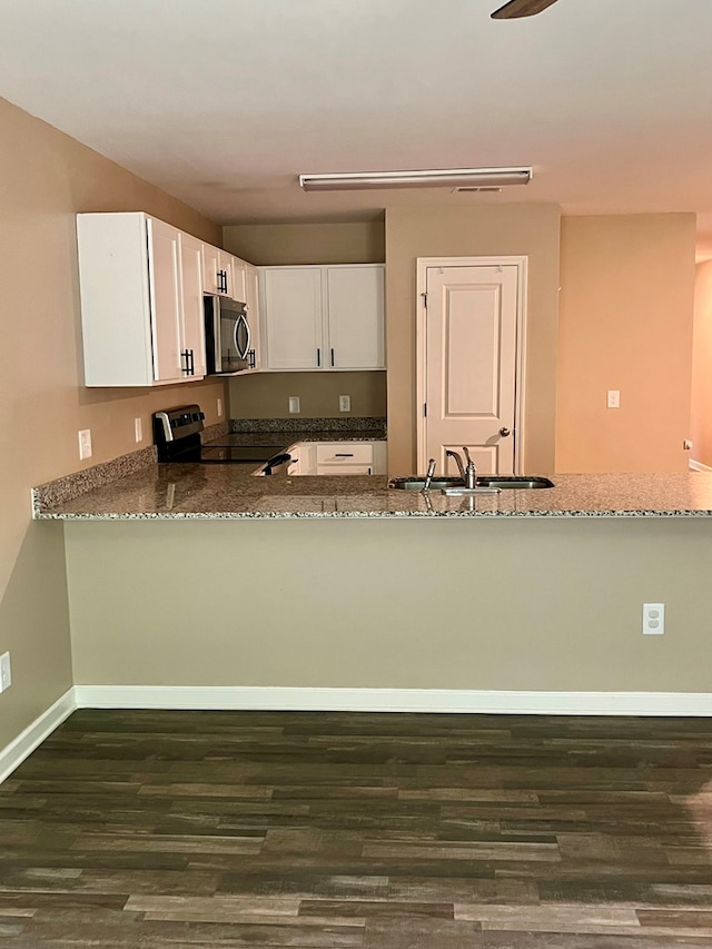 kitchen featuring a sink, dark stone counters, white cabinets, dark wood-style flooring, and appliances with stainless steel finishes