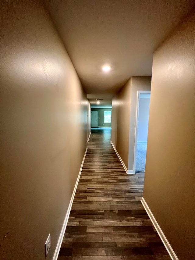 corridor with dark wood-style flooring and baseboards