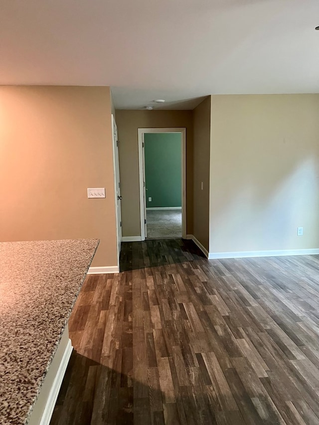 corridor featuring baseboards and dark wood-style floors