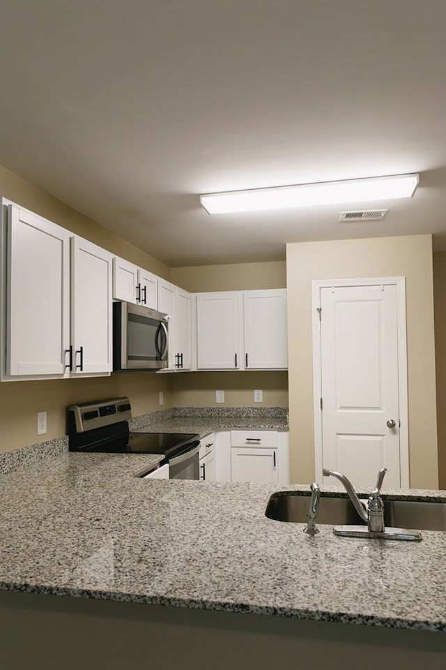 283 Parkland Way, Chatsworth, GA 30705 - kitchen featuring stainless steel appliances, light stone countertops, white cabinetry, and a sink