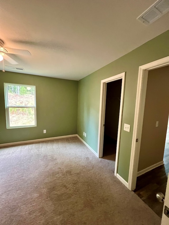 carpeted empty room with ceiling fan, baseboards, and visible vents