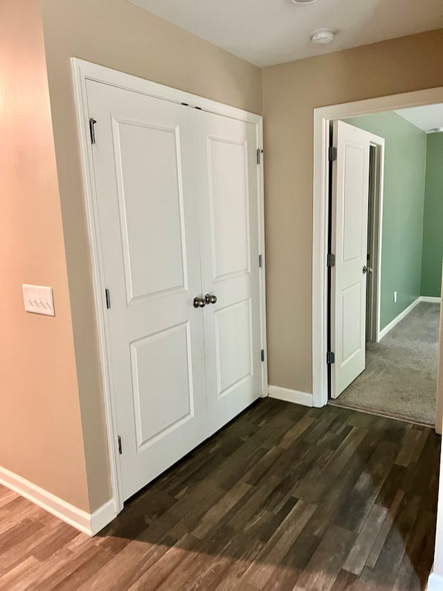 unfurnished bedroom with baseboards, dark wood-style flooring, and a closet