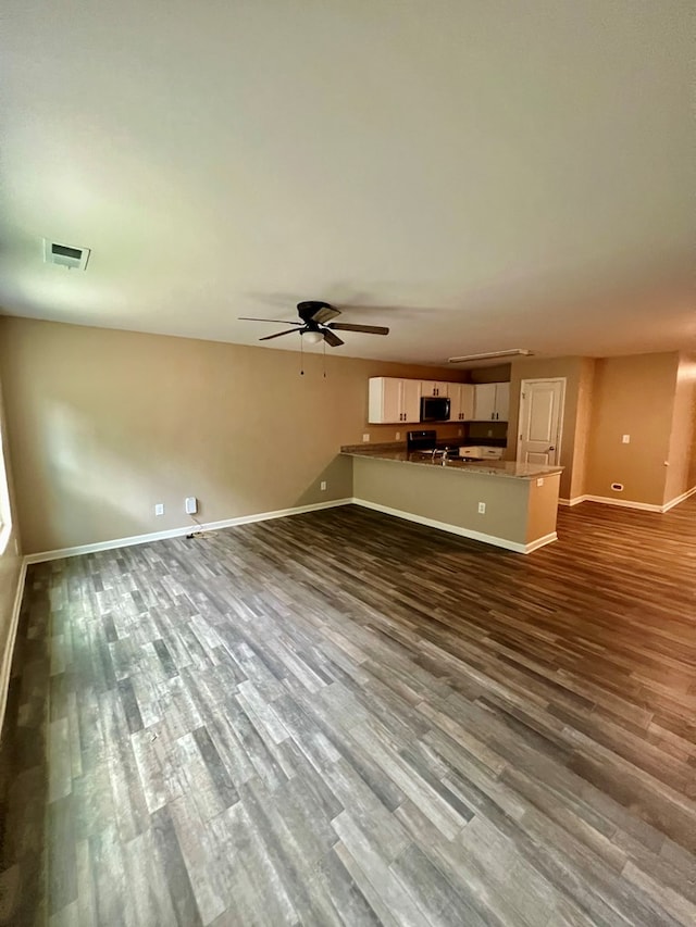 unfurnished living room with ceiling fan, baseboards, dark wood-style floors, and visible vents