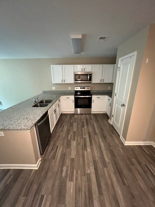 kitchen with dark wood-style flooring, stainless steel appliances, white cabinets, and a sink