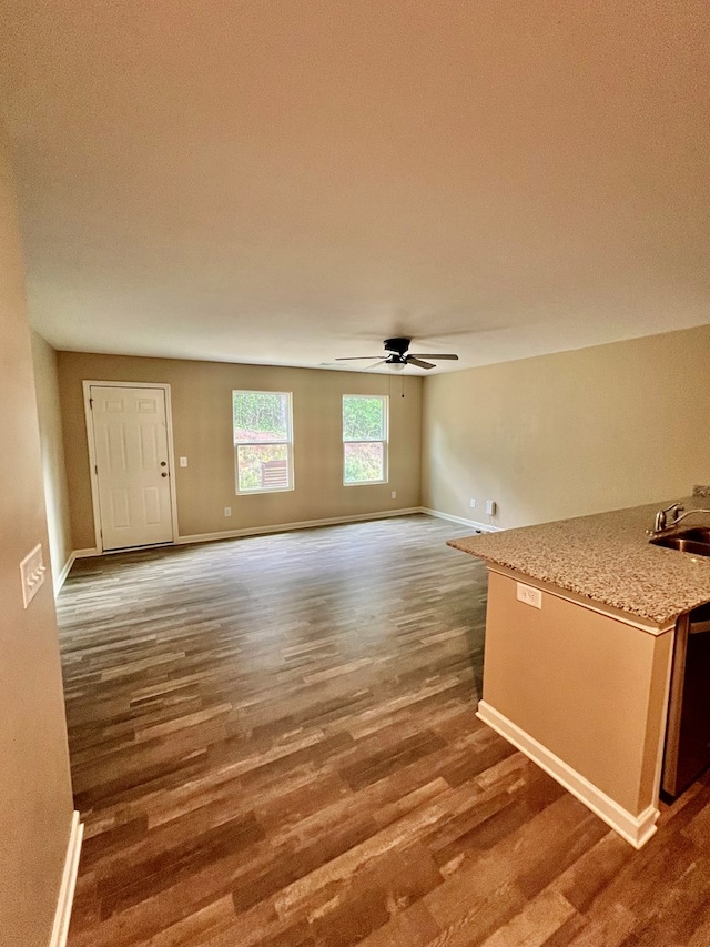 unfurnished living room with wood finished floors, baseboards, ceiling fan, and a sink