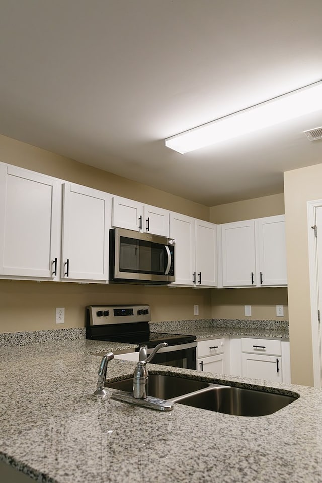 283 Parkland Way, Chatsworth, GA 30705 - kitchen featuring appliances with stainless steel finishes, white cabinetry, light stone countertops, and a sink