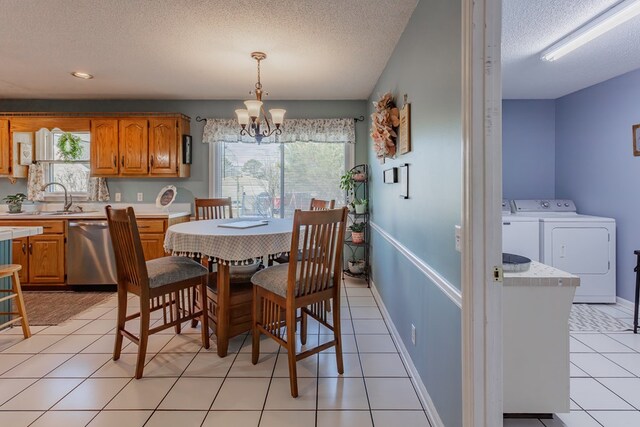 tiled dining area with a notable chandelier, sink, a textured ceiling, and independent washer and dryer