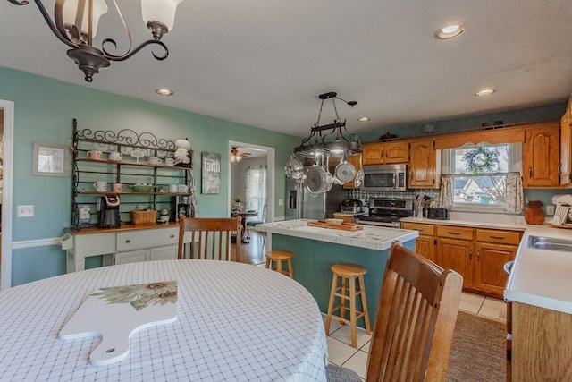 tiled dining room featuring sink, ceiling fan with notable chandelier, and a textured ceiling